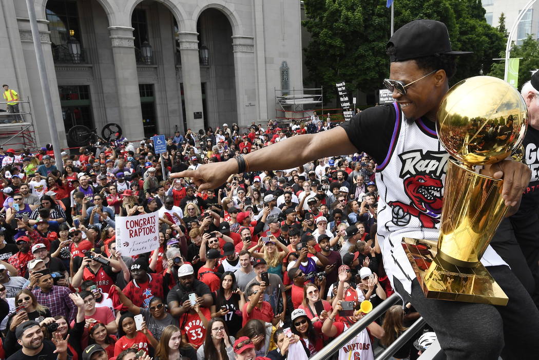 Toronto Raptors guard Kyle Lowry gestures towards fans while holding the Larry O'Brien Champion ...