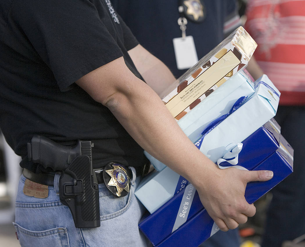 Las Vegas police carry boxes of See's Candy recovered at a residence at 1504 Cutler Drive, near ...