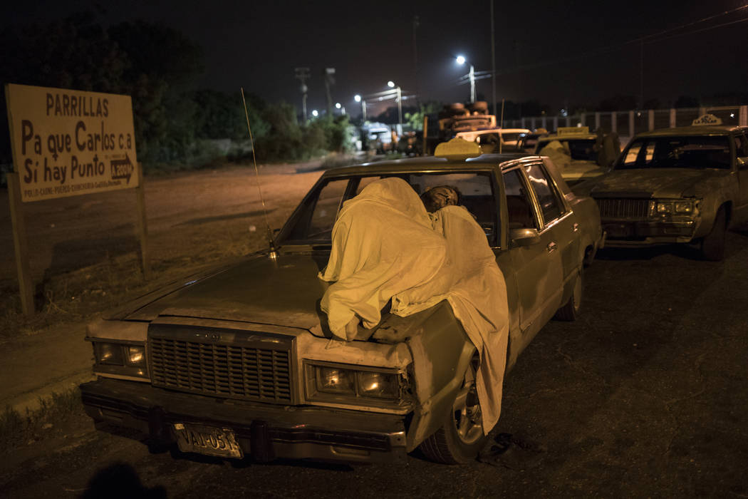 A man sleeps on top of his car as he waits in line to fill up outside a gas station in Maracaib ...