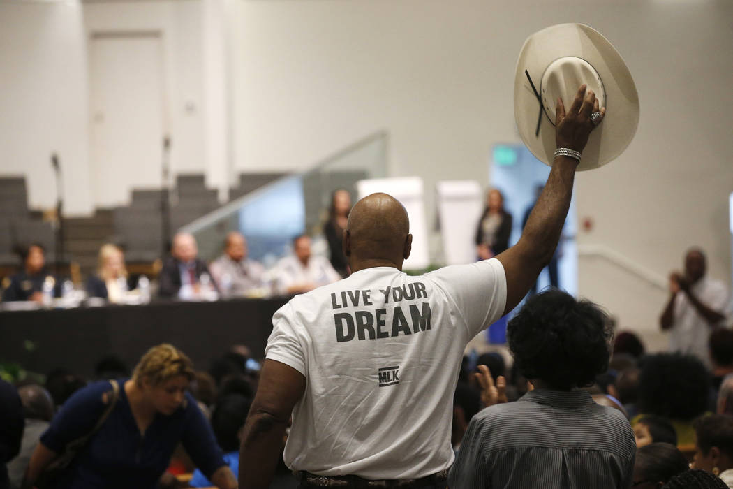 A Phoenix resident stands up to wave his cowboy hat in support of a speaker at a community meet ...