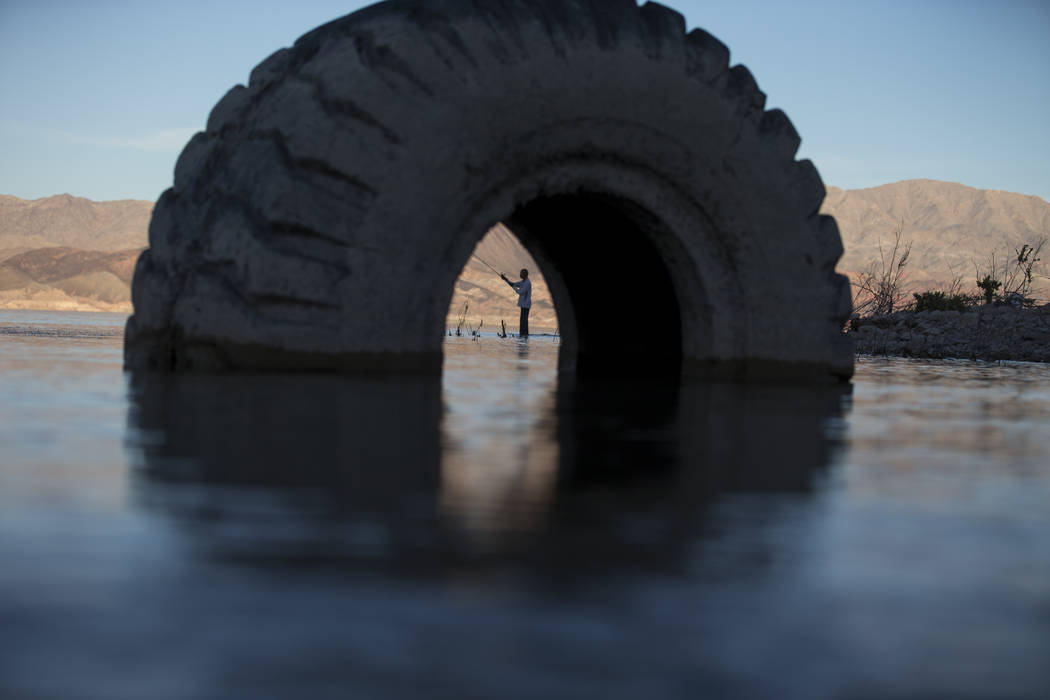 Ivan Lau of Las Vegas is seen through a partially submerged tire as he fishes near Boulder Harb ...