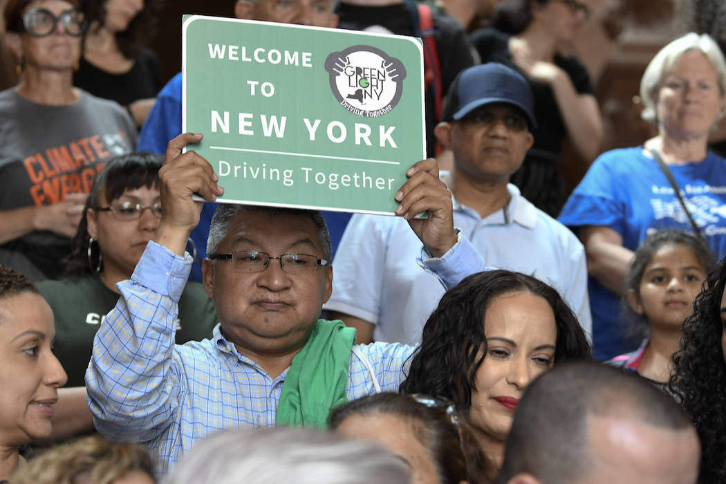 A man holds a sign as members of the state Assembly speak in favor of legislation of the Green ...