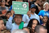 A man holds a sign as members of the state Assembly speak in favor of legislation of the Green ...