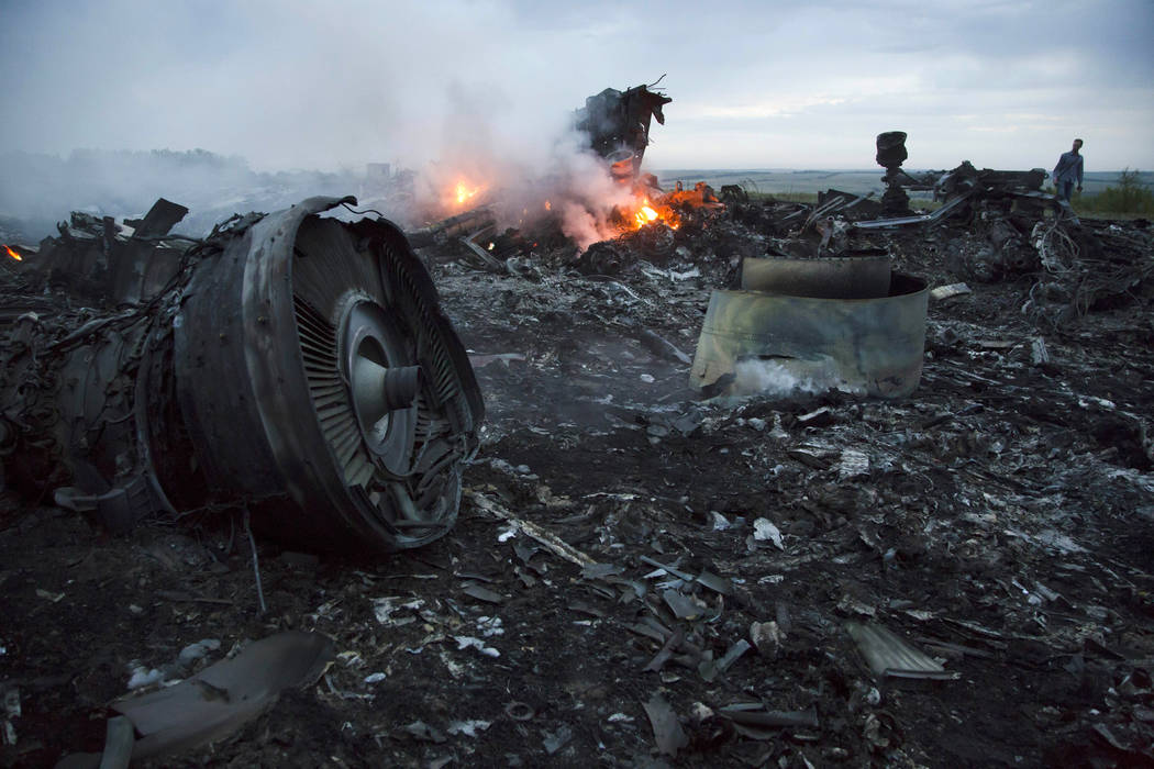 FILE - In this Thursday, July 17, 2014 file photo, a man walks amongst the debris at the crash ...