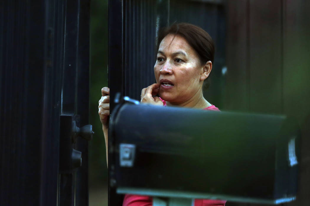 A woman watches as law enforcement officers surround a home where a gunman has taken refuge aft ...