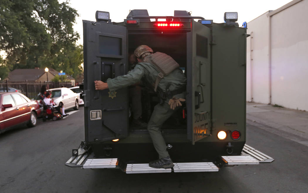 A law enforcement officer climbs into a tactical vehicle during a standoff with an armed suspec ...