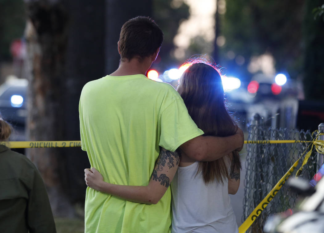 A man and woman watch as law enforcement officers surround a home where a gunman has taken refu ...