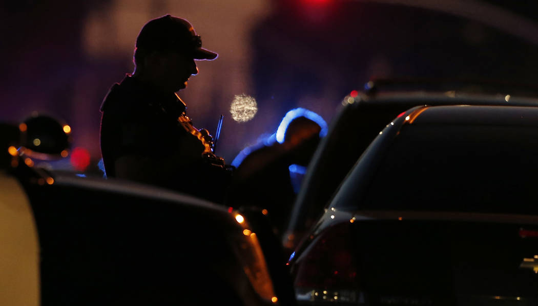 A law enforcement officer mans a barricade near a home that authorities have surrounded where a ...