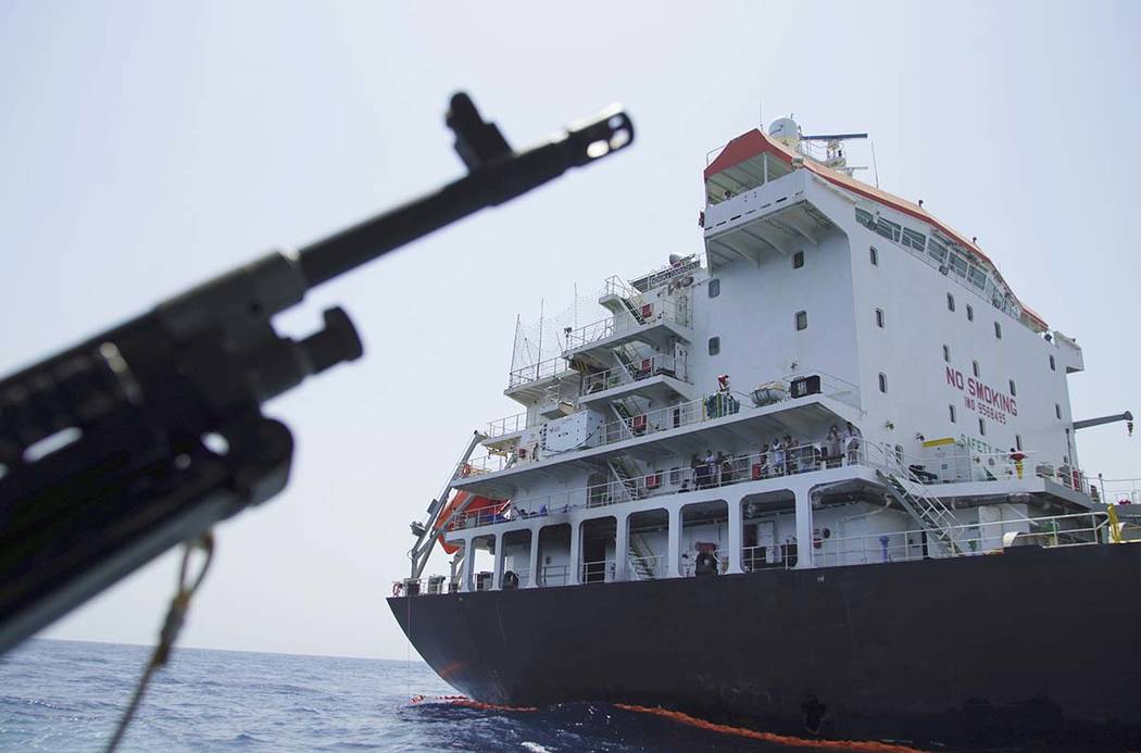 Sailors stand on deck above a hole the U.S. Navy says was made by a limpet mine on the damaged ...