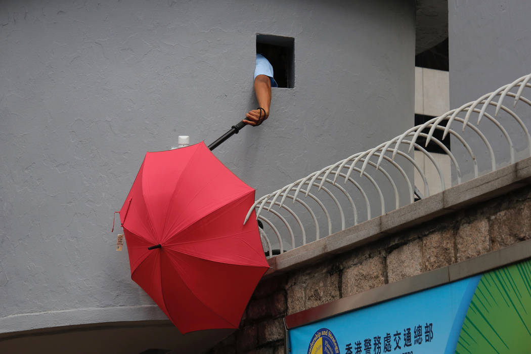 A police officer tries to remove an umbrella blocking the view of security cameras outside the ...