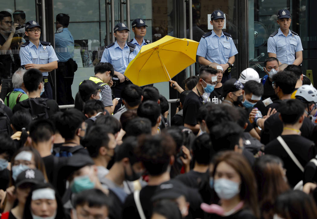 A protester holds out a yellow umbrella towards a line of police officers in Hong Kong Friday, ...