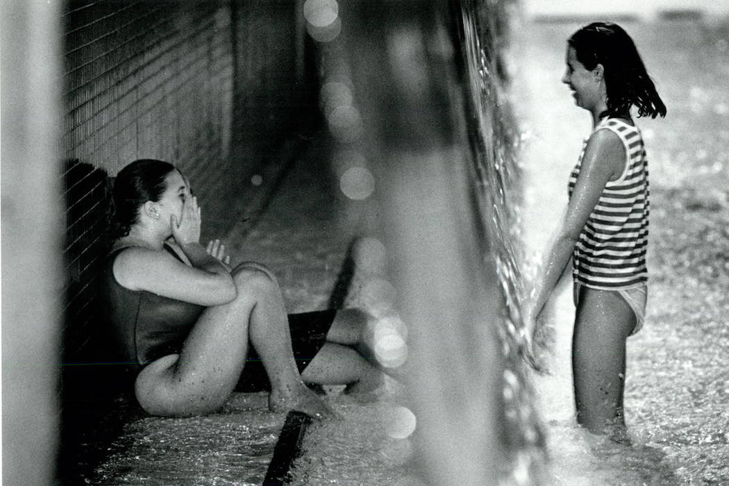 Friends talk to each other through a waterfall at Wet 'n Wild on Las Vegas Boulevard during a s ...