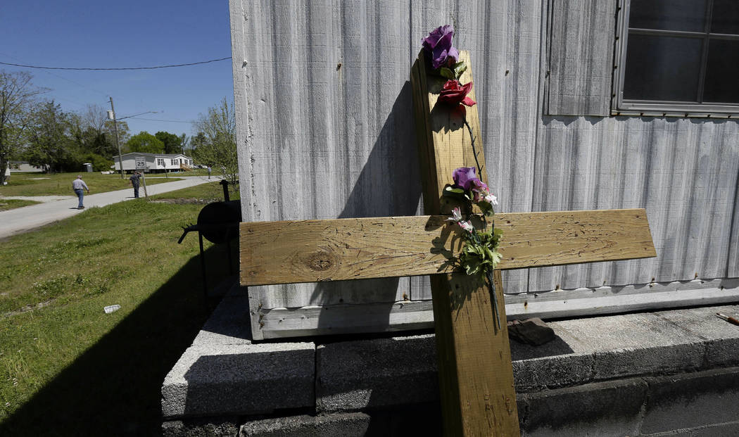 In this photo taken Wednesday, April 17, 2019, a cross leans against an abandoned house trailer ...