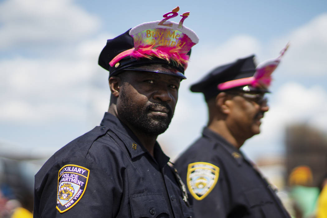 NYPD officers stand guard as as parade attendees in costume make their way along Surf Avenue du ...