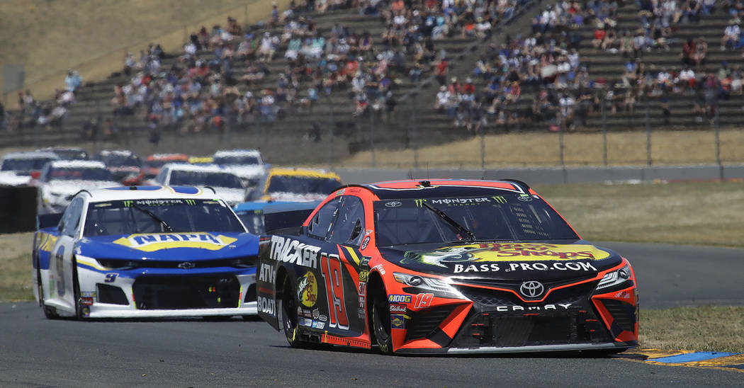 Martin Truex Jr., right, leads through a turn during a NASCAR Sprint Cup Series auto race Sunda ...