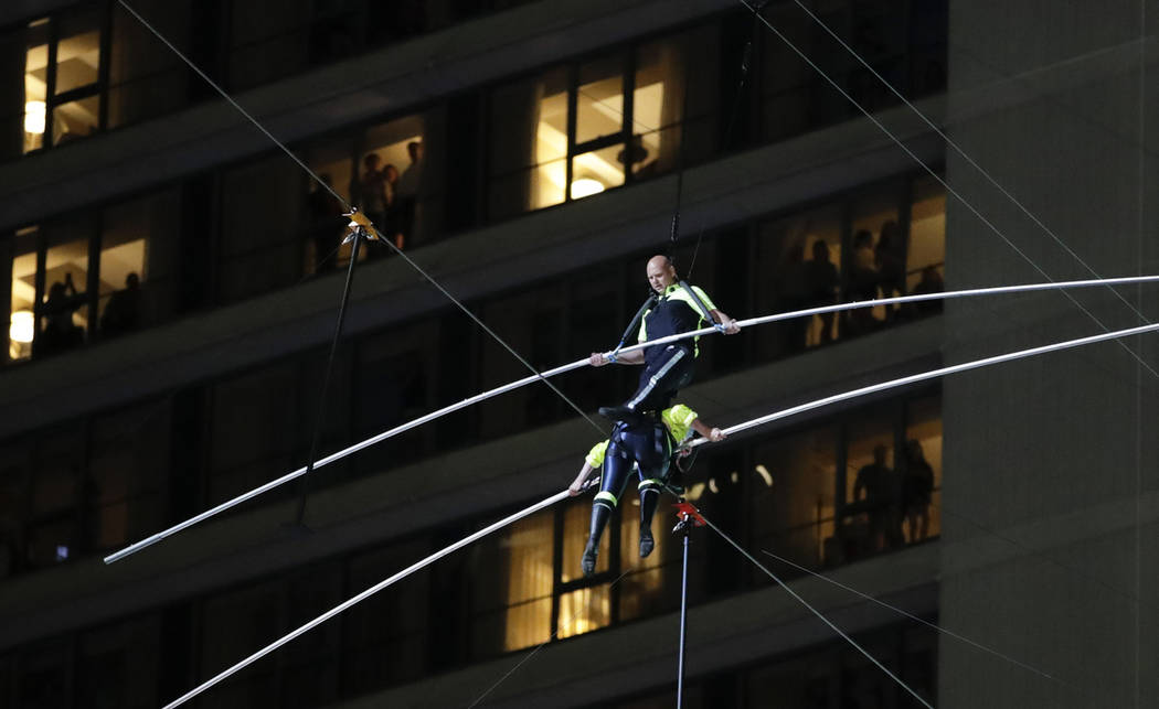 Aerialists Nik Wallenda, top, steps over his sister Lijana as they walk on a high wire above Ti ...