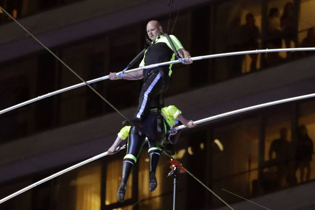 Aerialists Nik Wallenda, top, steps over his sister Lijana as they walk on a high wire above Ti ...