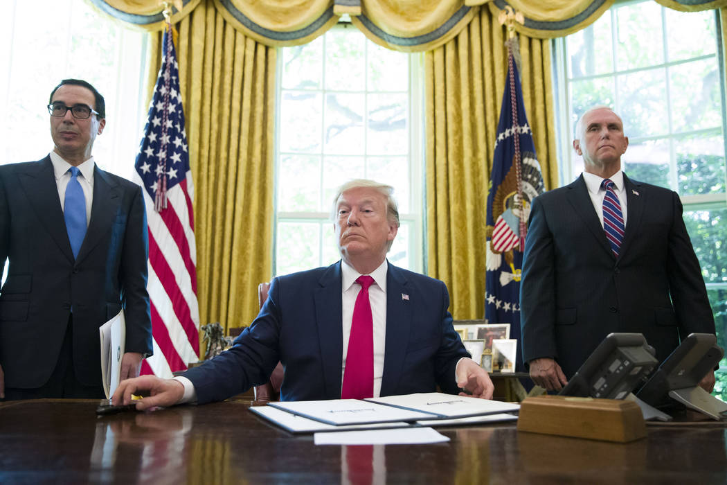 President Donald Trump listens to a reporter's question after signing an executive order to inc ...