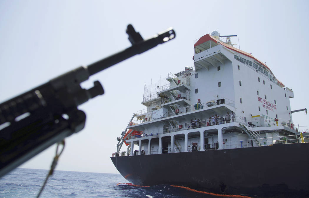 Sailors stand on deck above a hole the U.S. Navy says was made by a limpet mine on the damaged ...