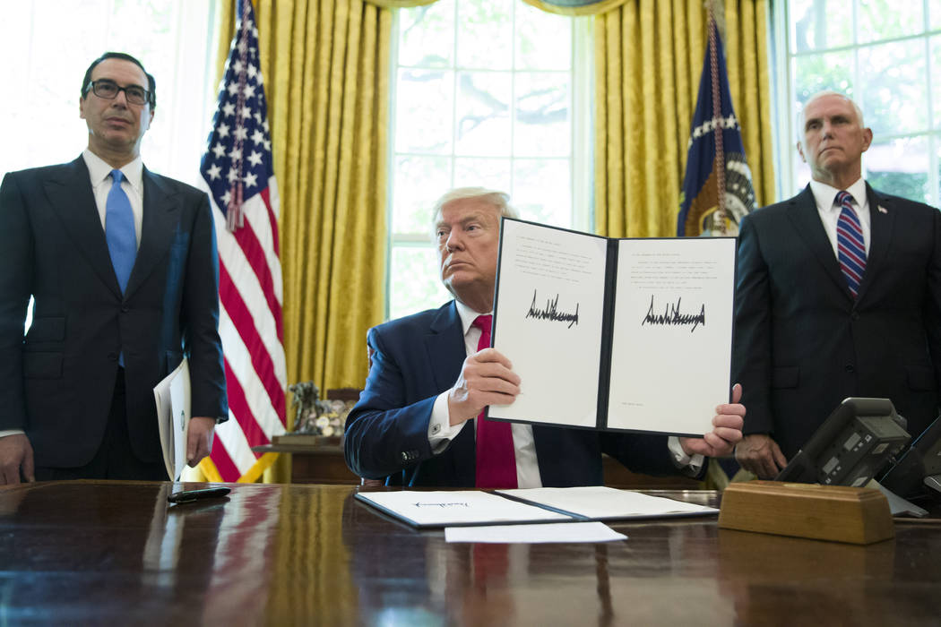 President Donald Trump holds up a signed executive order to increase sanctions on Iran, in the ...