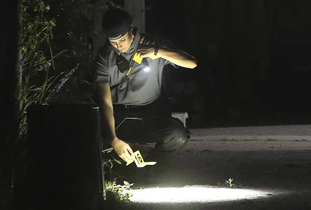 Technicians process the driveway of a home as Salt Lake City Police serve a search warrant at t ...