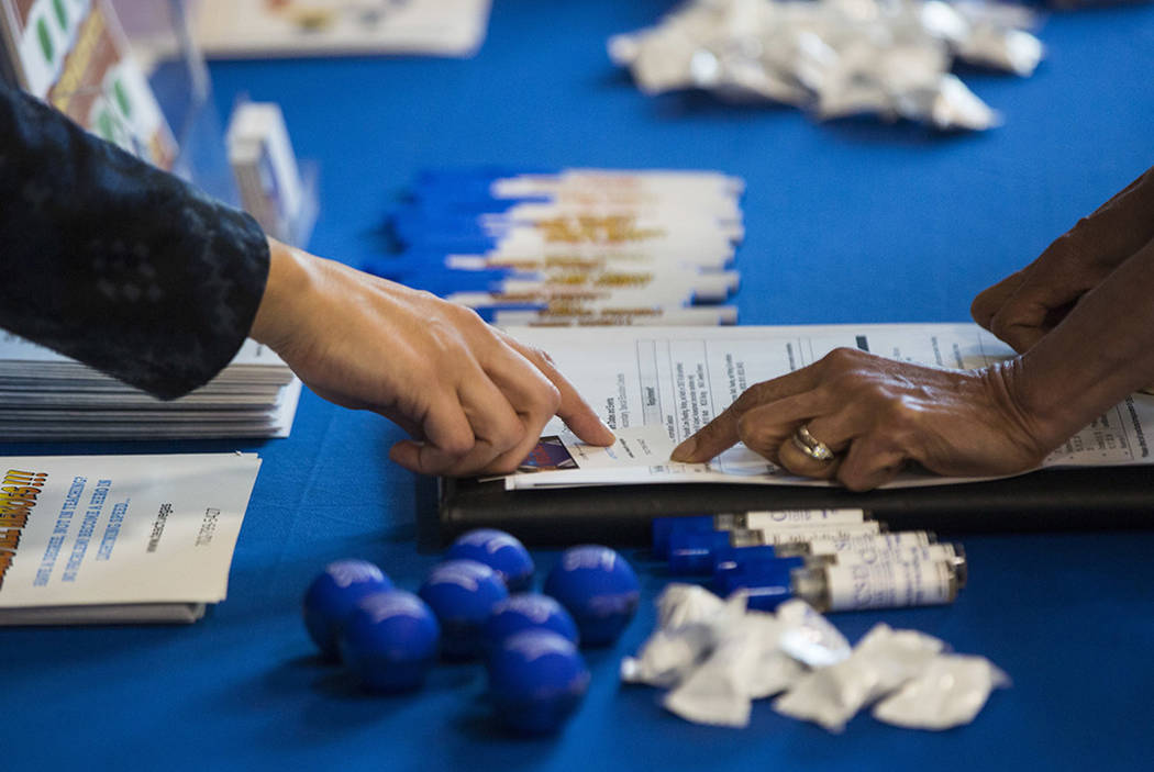 Veronica Arreguin, a personnel analyst with the Clark County School District, left, assists a p ...