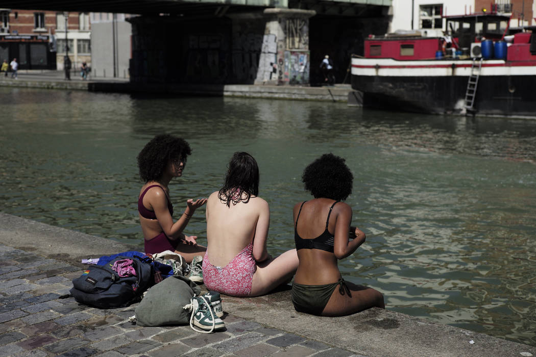 Girls wearing swimsuits sit along the Canal de l'Ourcq in Paris, Friday, June 28, 2019. Schools ...