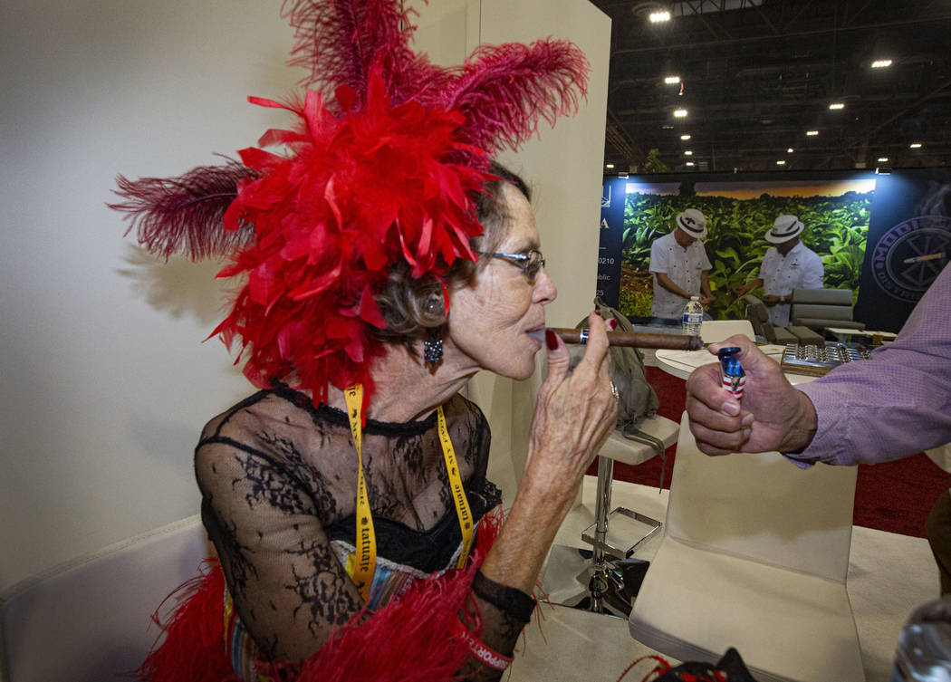 Suzanne Wilson, owner of Smoke Signals in Tombstone, Ariz., puffs a cigar from the help of Jack ...