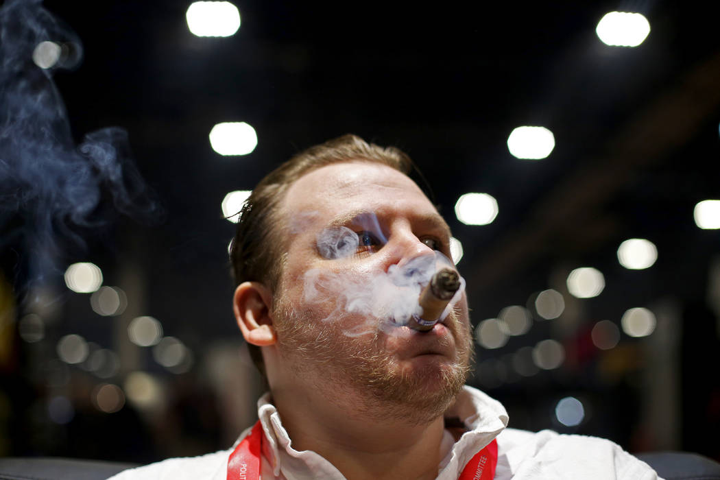Ethan Bradon smokes a cigar at the Serino Cigar Company booth at the International Premium Ciga ...