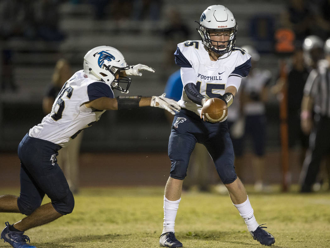 Foothill quarterback Koy Riggin (15) hands off the ball to running back Mario Armendariz (26 ...