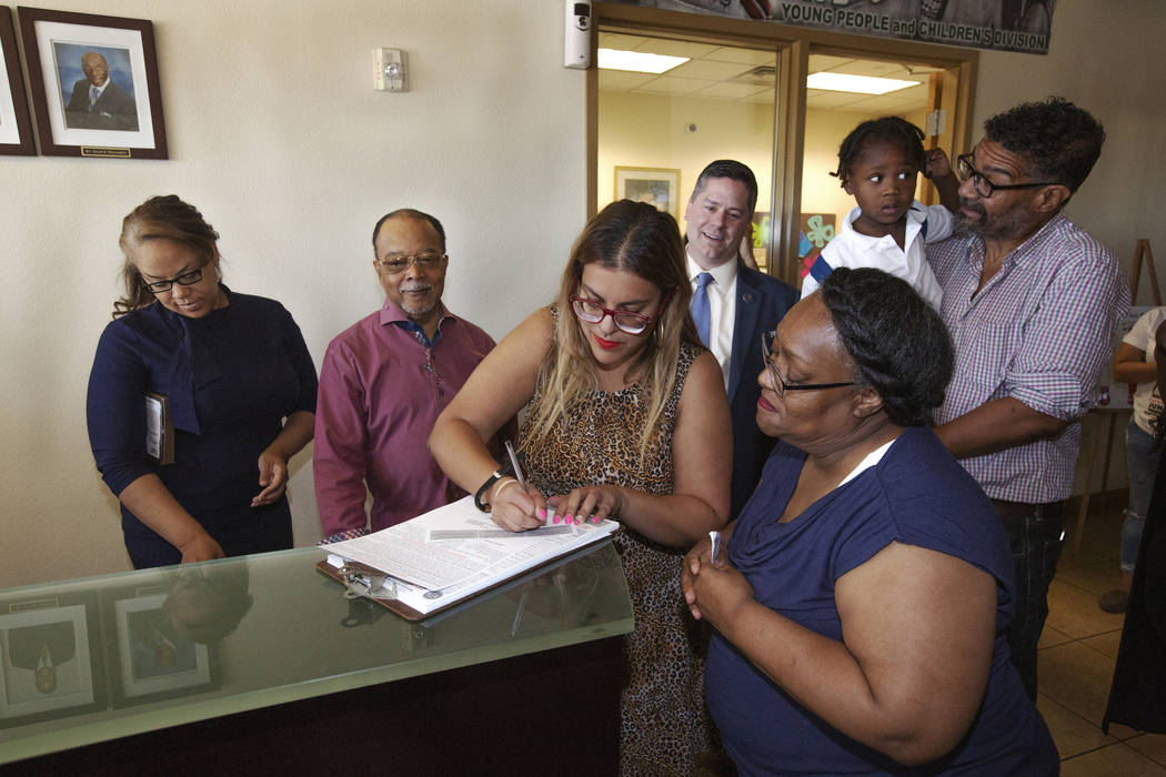 Ora Watkins, right, looks on as she receives help with her voter registration from Emily Zamora ...