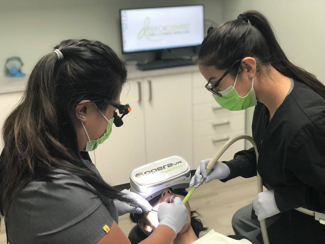 Dr. Dee Dee Meevasin, left, works on a patient who is using OperaVR, which can ease pain and an ...