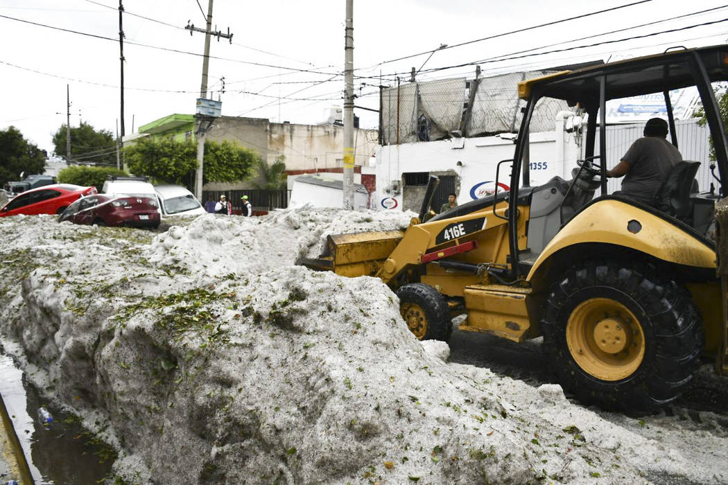 In this photo released by Jalisco State Civil Defense Agency, a bulldozer removes hail filling ...