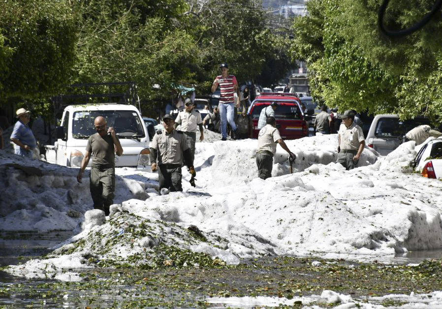 In this photo released by Jalisco State Civil Defense Agency, people work to remove hail from t ...