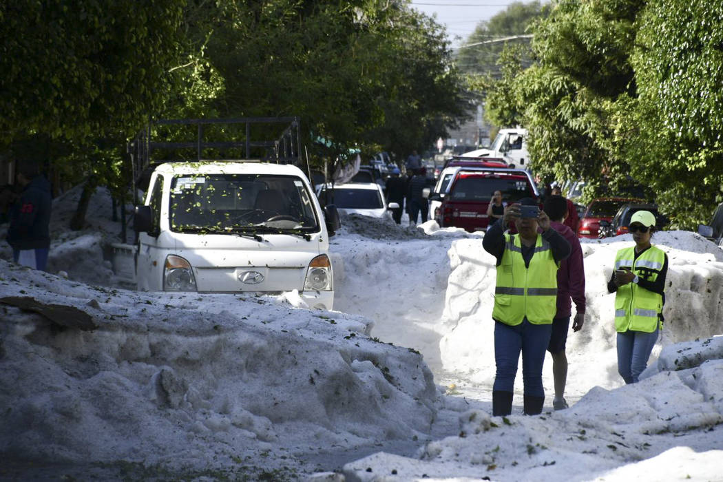 In this photo released by Jalisco State Civil Defense Agency, people take pictures of the stree ...