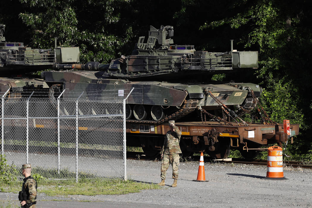 Military police walk near Abrams tanks on a flat car in a rail yard, Monday, July 1, 2019, in W ...