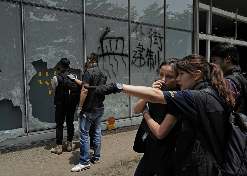 Plain-clothed police officers investigate near the broken glasses outside Legislative Council b ...