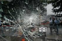 Police officers stand guard near a broken glass outside Legislative Council building in Hong Ko ...