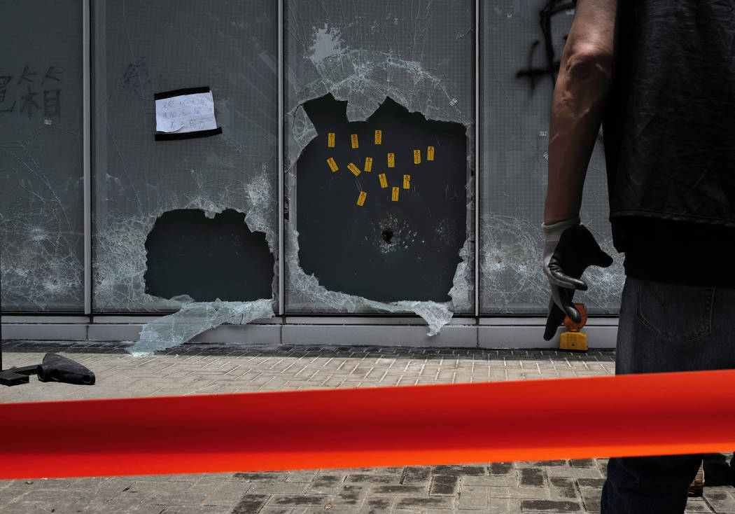 A police officer stands guard near the broken glasses outside Legislative Council building in H ...