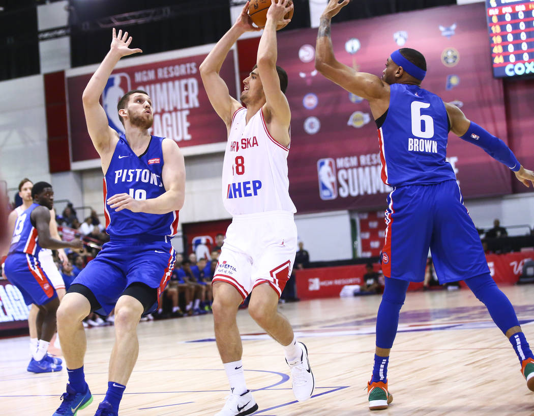 Croatia's Roko Badzim (18) moves the ball between Detroit Pistons' Sviatoslav Mykhailiuk, left, ...