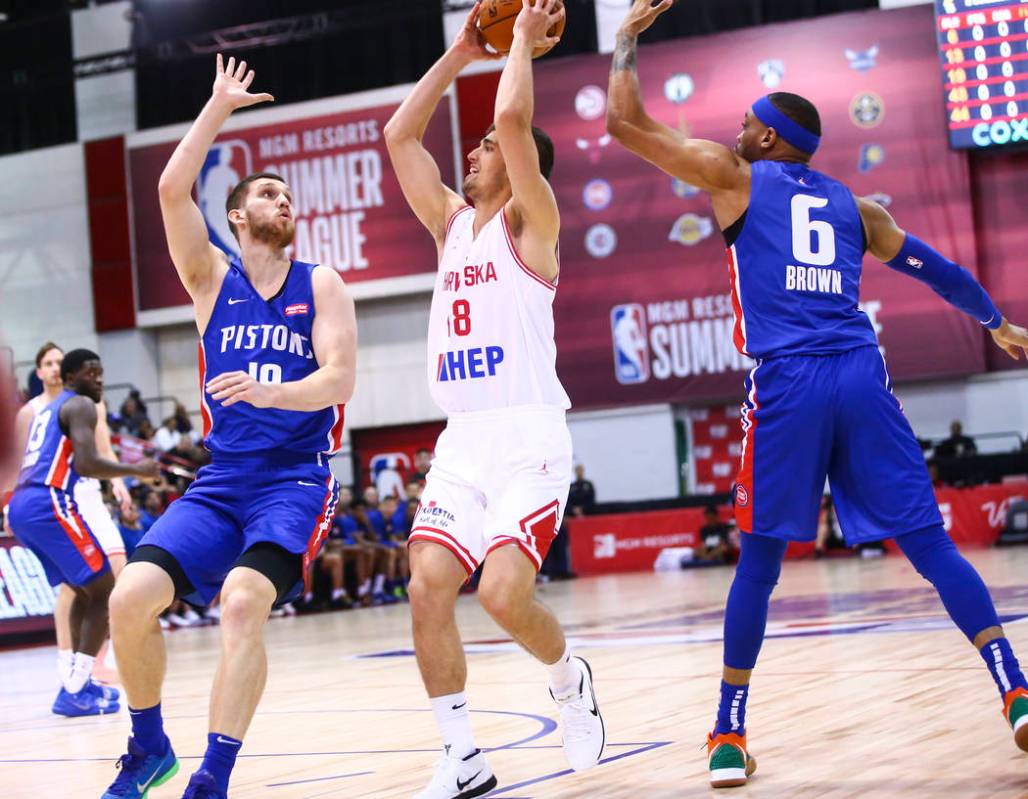 Croatia's Roko Badzim (18) moves the ball between Detroit Pistons' Sviatoslav Mykhailiuk, left, ...