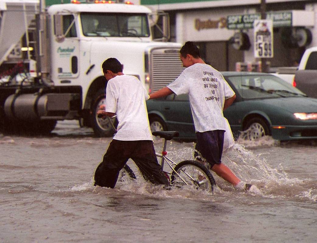 Two boys push a bicycle through the intersection of Charleston and Lamb on Thursday, July 8, 19 ...