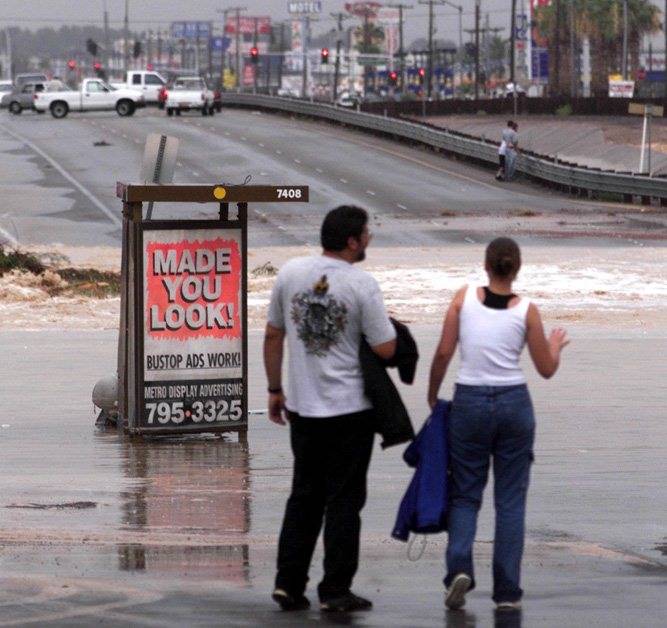 On lookers watch the flood waters crossing Boulder Highway near Sahara. (Las Vegas Review-Journ ...