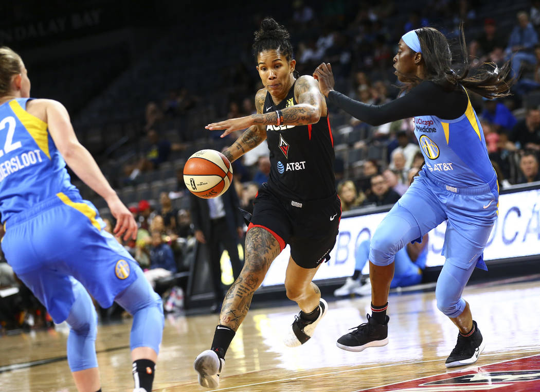 Las Vegas Aces' Tamera Young, center, drives to the basket against Chicago Sky's Kahleah Copper ...