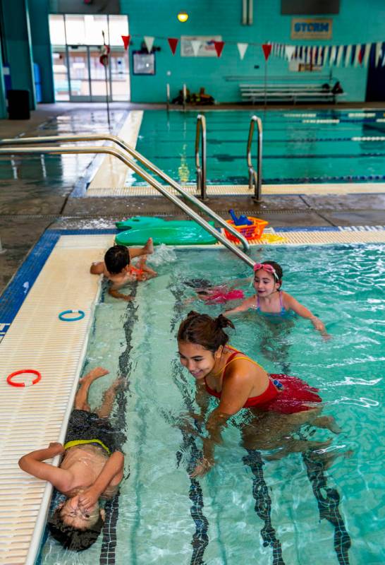 Swim instructor Shanneal Ocular, center, watches her students Stefan Flores, 4, foreground, try ...