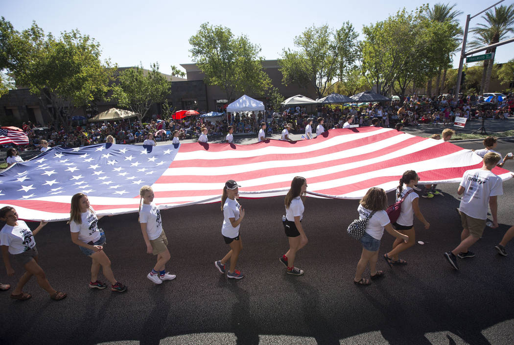 Members of the Palo Verde High School track team march with a giant American Flag during the Su ...