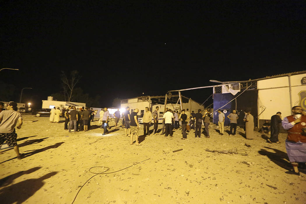 Workers gather at a detention center after an airstrike in Tajoura, east of Tripoli Wednesday, ...