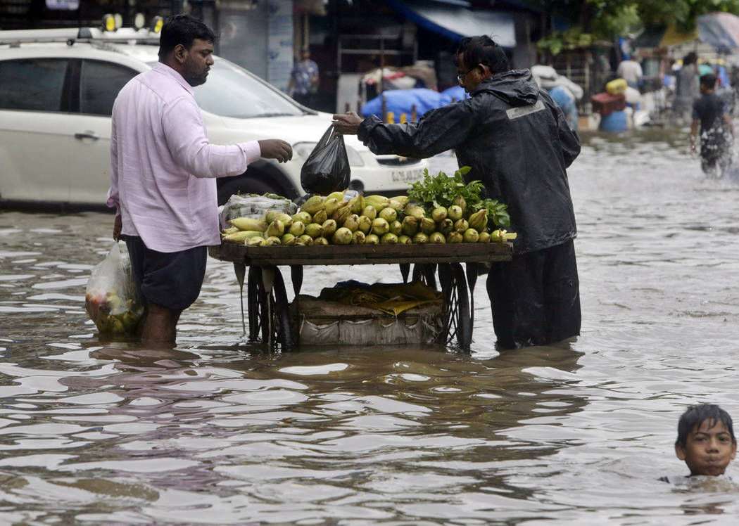 A boy plays as a street vendor attends to a customer in a waterlogged street following heavy ra ...