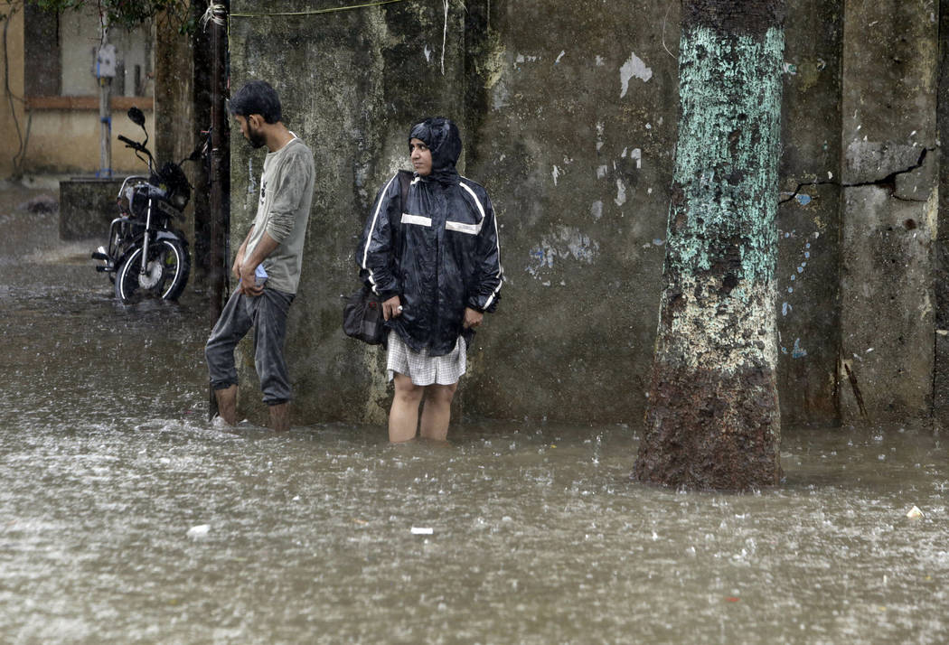 People wade through a waterlogged street following heavy rains in Mumbai, India, Tuesday, July ...