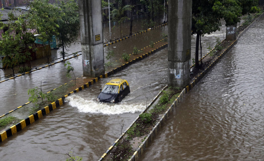 A car moves through a waterlogged street following heavy rains in following heavy rains in Mumb ...